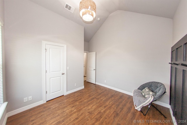 unfurnished bedroom with dark hardwood / wood-style flooring, lofted ceiling, and an inviting chandelier