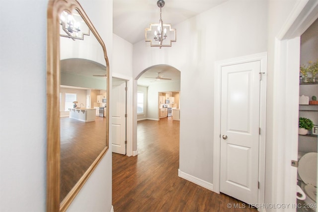 corridor featuring a chandelier, a towering ceiling, and dark hardwood / wood-style flooring