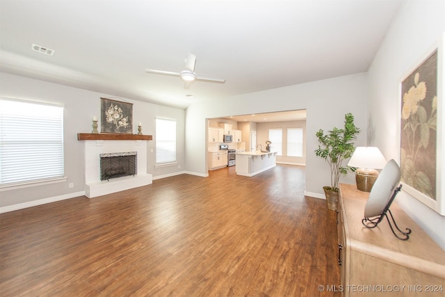 unfurnished living room featuring a wealth of natural light, dark hardwood / wood-style flooring, and ceiling fan