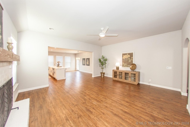 unfurnished living room with ceiling fan, hardwood / wood-style floors, and a brick fireplace