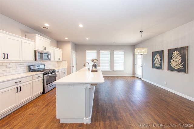 kitchen with white cabinets, dark hardwood / wood-style flooring, stainless steel appliances, and a center island with sink