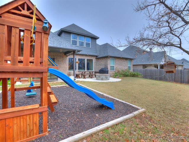 view of jungle gym featuring a patio, an outdoor fire pit, and a lawn