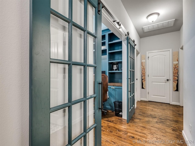 corridor with a barn door and dark hardwood / wood-style floors