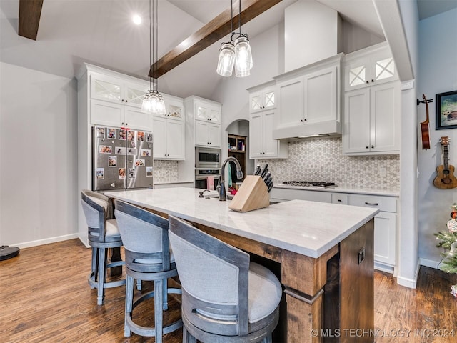 kitchen with appliances with stainless steel finishes, white cabinetry, a kitchen island with sink, and beam ceiling