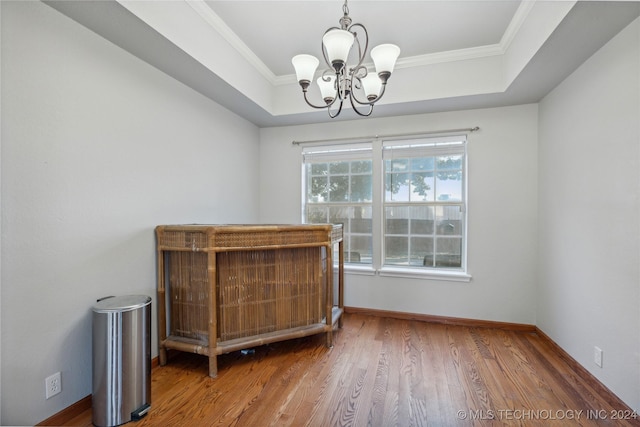 bedroom with hardwood / wood-style floors, ornamental molding, a tray ceiling, and a chandelier