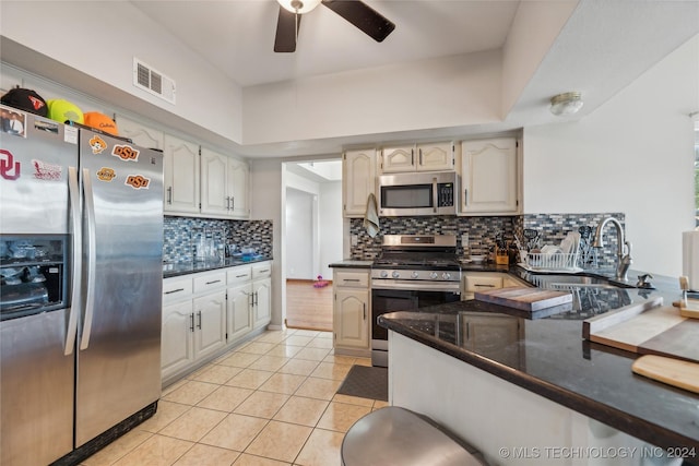 kitchen with decorative backsplash, kitchen peninsula, stainless steel appliances, ceiling fan, and light tile patterned floors