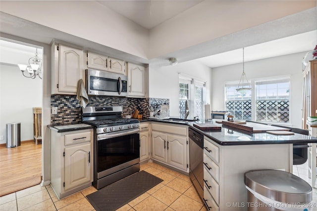 kitchen featuring a healthy amount of sunlight, light tile patterned flooring, kitchen peninsula, and stainless steel appliances