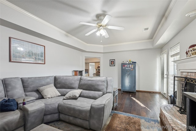 living room with a fireplace, dark hardwood / wood-style flooring, ceiling fan, and ornamental molding