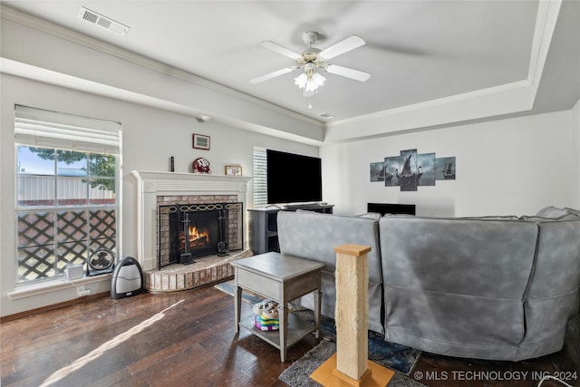 living room featuring ornamental molding, a brick fireplace, ceiling fan, and dark wood-type flooring