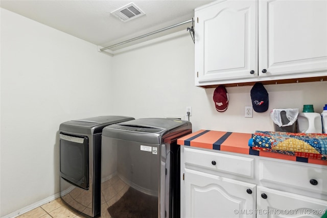 laundry area featuring separate washer and dryer, light tile patterned floors, and cabinets