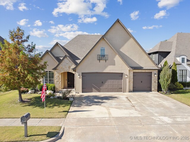 french country inspired facade with stone siding, an attached garage, concrete driveway, a front lawn, and stucco siding