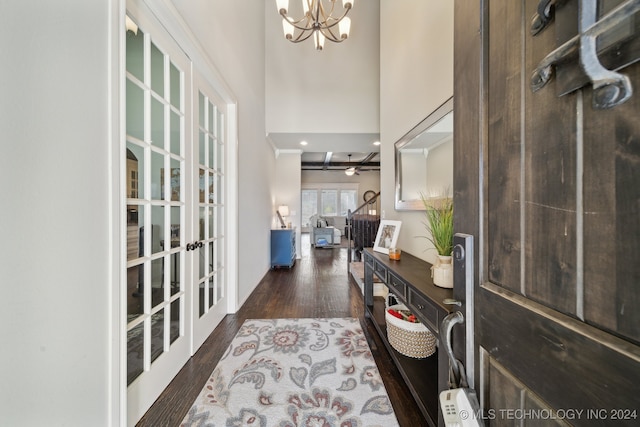 foyer with dark hardwood / wood-style flooring, a towering ceiling, ceiling fan with notable chandelier, and french doors