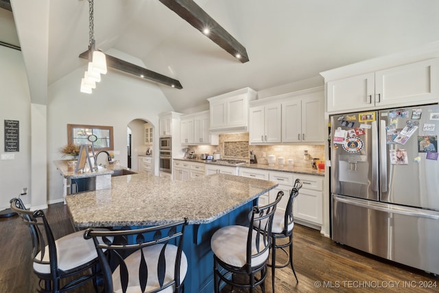 kitchen featuring white cabinets, appliances with stainless steel finishes, a kitchen bar, and beamed ceiling