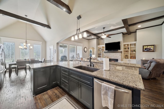 kitchen featuring pendant lighting, sink, stainless steel appliances, light stone countertops, and a center island with sink