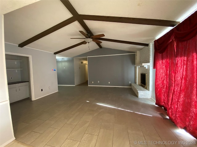 unfurnished living room with a fireplace, vaulted ceiling with beams, hardwood / wood-style flooring, and ceiling fan