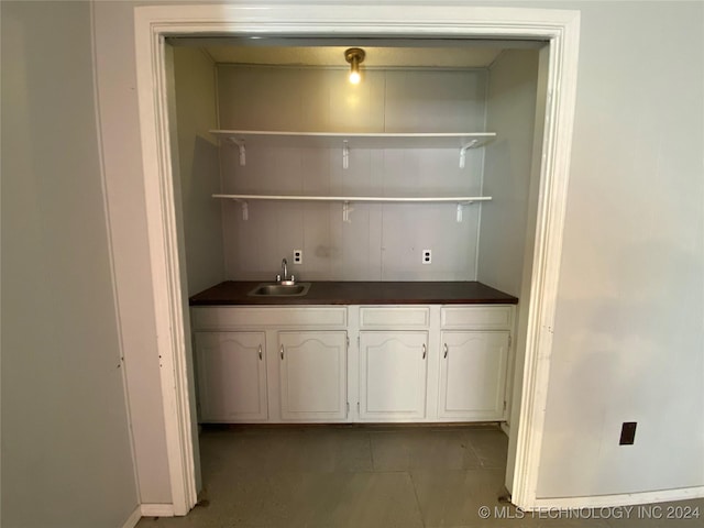 bar with white cabinetry and sink