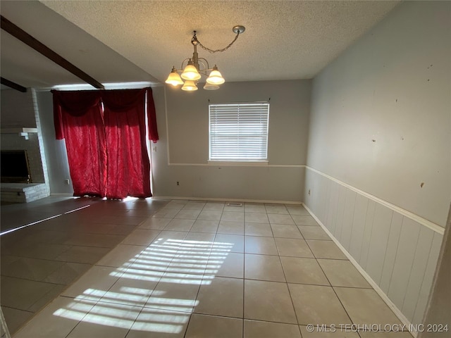 unfurnished dining area featuring tile patterned flooring, a chandelier, a textured ceiling, and a brick fireplace