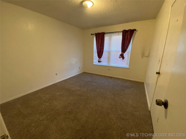 carpeted empty room featuring a textured ceiling