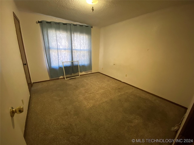 carpeted empty room with a textured ceiling