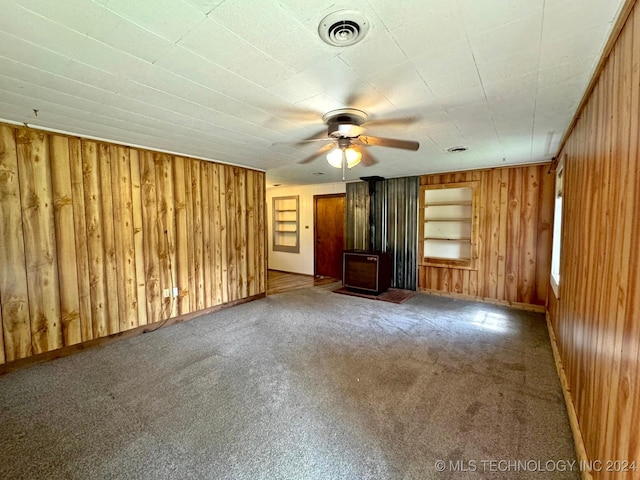 unfurnished living room featuring carpet flooring, ceiling fan, and wooden walls