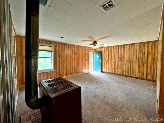 unfurnished living room with ceiling fan, carpet, and wood walls