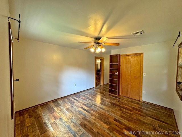 unfurnished bedroom with ceiling fan, a closet, and dark hardwood / wood-style floors