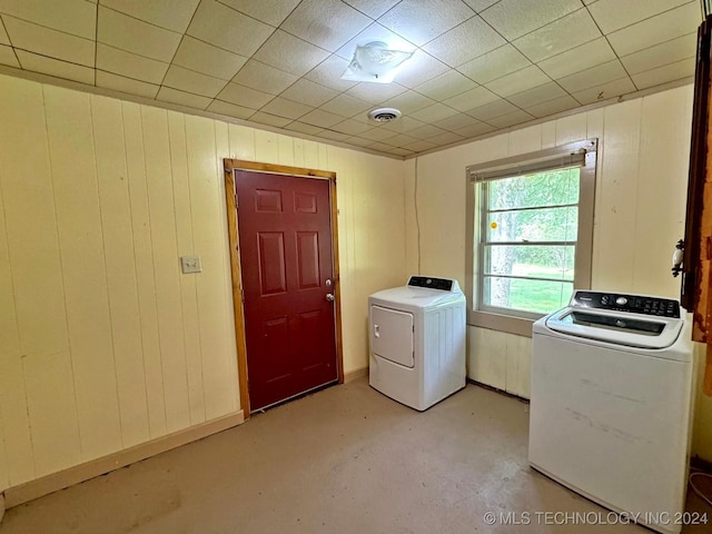 clothes washing area featuring washer and clothes dryer and wood walls