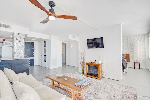 living room featuring ceiling fan, concrete flooring, and a fireplace