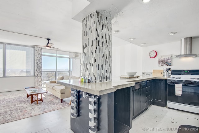 kitchen featuring kitchen peninsula, white range, ceiling fan, and wall chimney range hood