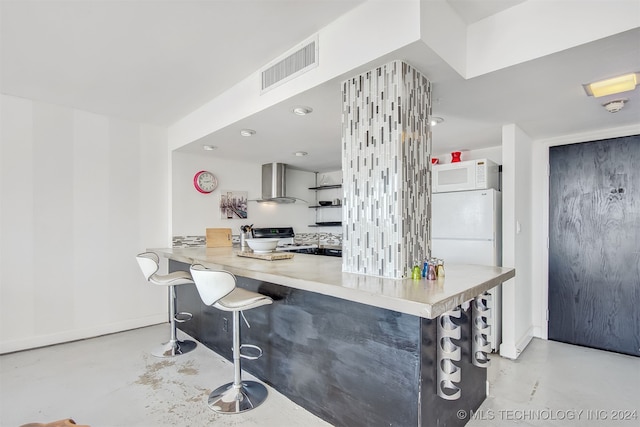 kitchen with wall chimney exhaust hood, a kitchen bar, kitchen peninsula, and stainless steel range oven