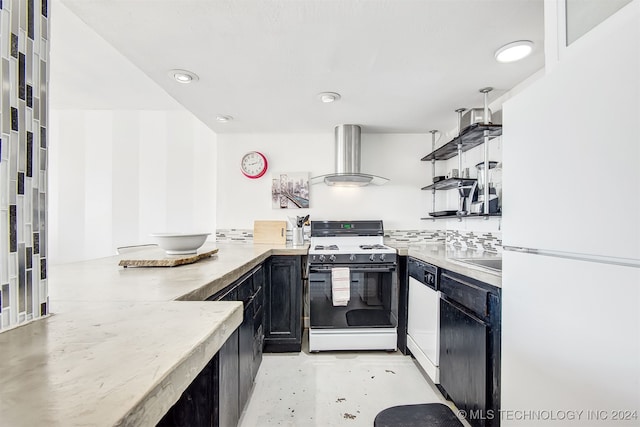 kitchen featuring kitchen peninsula, white appliances, hanging light fixtures, and wall chimney exhaust hood