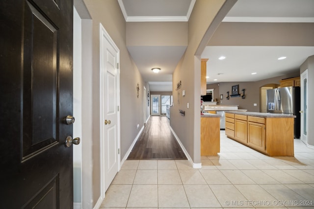 hallway with light tile patterned floors and ornamental molding