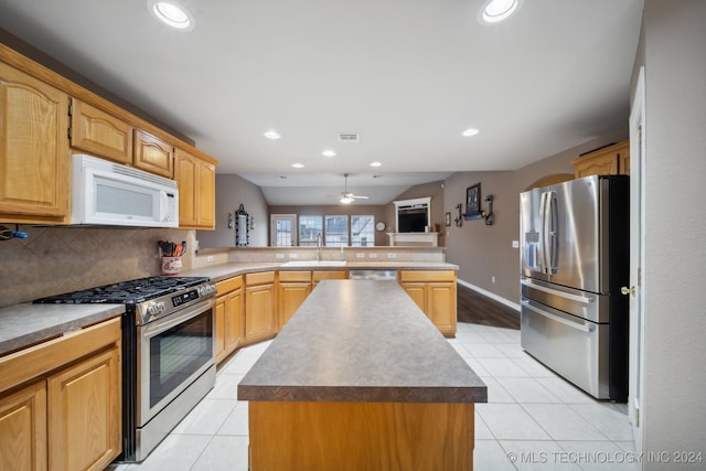 kitchen with light tile patterned flooring, ceiling fan, a kitchen island, kitchen peninsula, and stainless steel appliances