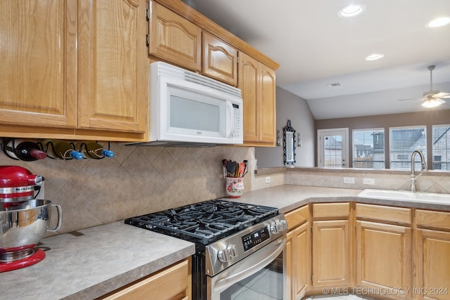 kitchen featuring tasteful backsplash, vaulted ceiling, ceiling fan, sink, and stainless steel stove