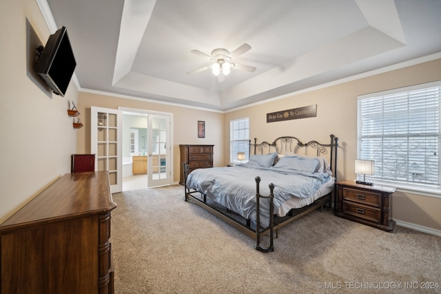 carpeted bedroom featuring ensuite bathroom, a tray ceiling, and multiple windows