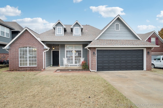 view of front of house featuring a porch, a front yard, and a garage