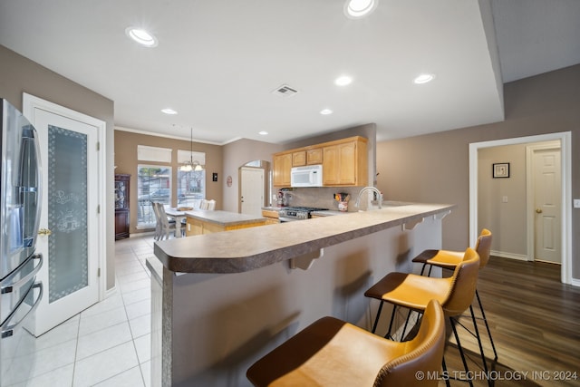 kitchen with stainless steel appliances, kitchen peninsula, crown molding, a breakfast bar area, and decorative backsplash