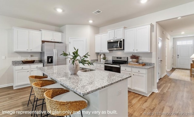 kitchen with stainless steel appliances, a kitchen breakfast bar, an island with sink, and white cabinets