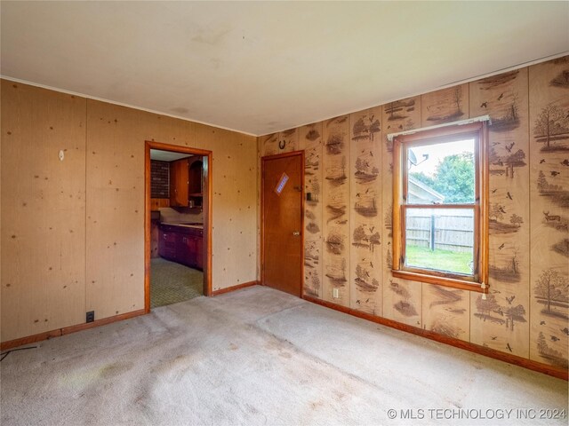 carpeted spare room featuring wood walls
