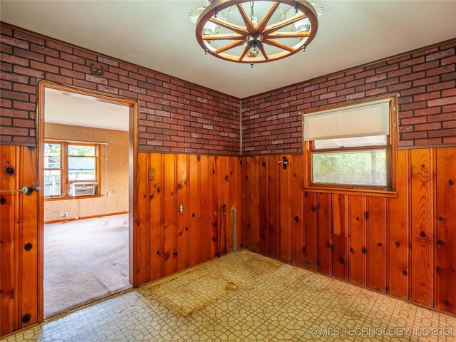 unfurnished room with cooling unit, wood walls, and brick wall
