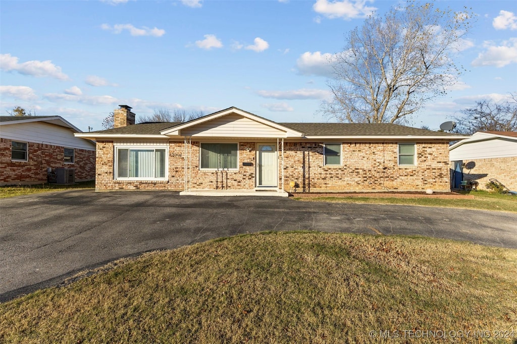 ranch-style home with central air condition unit and a front lawn