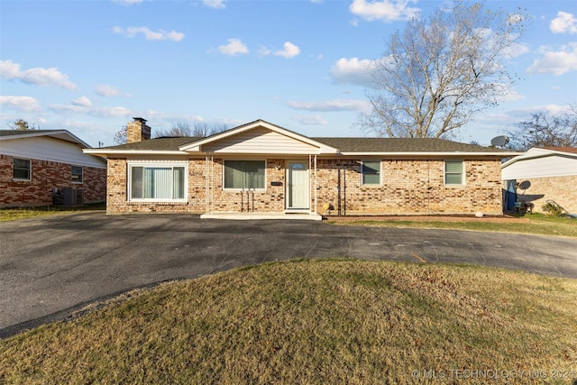 ranch-style home with central air condition unit and a front lawn