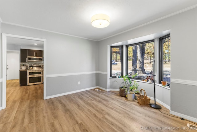 spare room featuring ornamental molding, light hardwood / wood-style floors, and a healthy amount of sunlight