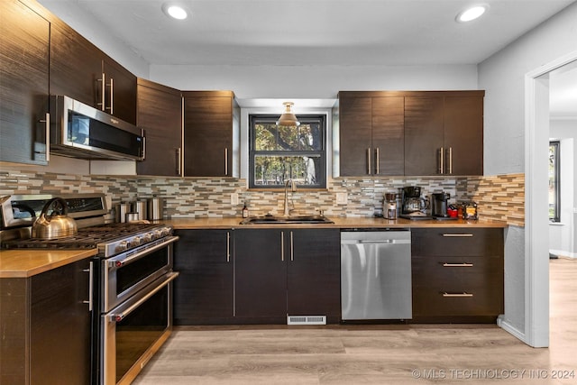 kitchen featuring a wealth of natural light, sink, stainless steel appliances, and light wood-type flooring