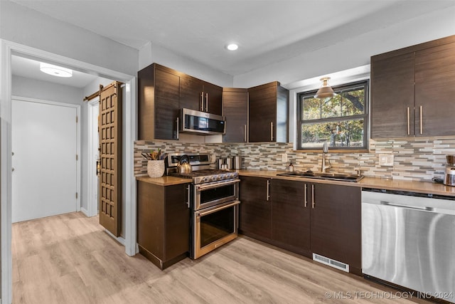 kitchen with dark brown cabinetry, sink, light hardwood / wood-style flooring, and appliances with stainless steel finishes