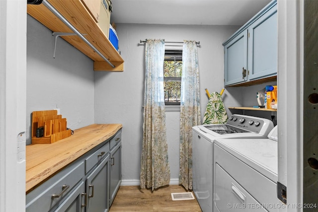 laundry area with independent washer and dryer, cabinets, and hardwood / wood-style flooring