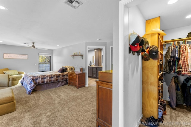 bedroom with light carpet, connected bathroom, a closet, and ceiling fan