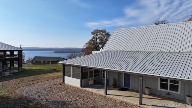 rear view of property featuring a patio, a water view, and a sunroom