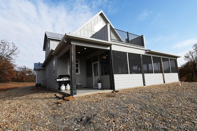 view of front facade featuring a sunroom, a balcony, and a patio