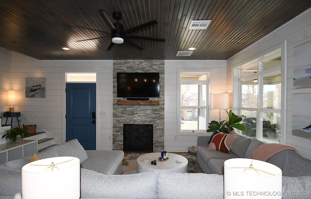 living room featuring wooden walls, a fireplace, ceiling fan, and wooden ceiling